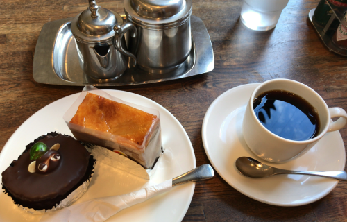扇堂(松本駅前店)の手前・左から「たぬきケーキ」「りんごのケーキ」ブラックコーヒー。奥にミルクと砂糖をそれぞれ入れた銀の器。木のテーブル