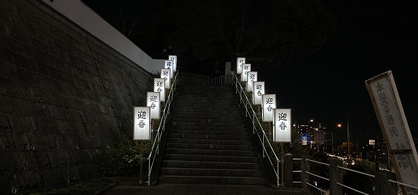 石段の左右に「迎春」と書かれた行灯がズラリと並んで新年へのゲートのように見える寺社の夜景